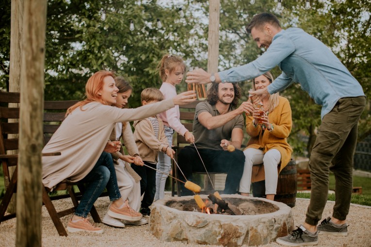 A group of people toasting marshmallows around a fire pit.
