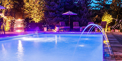 In-Ground Swimming Pool with fountain jets lit up at night