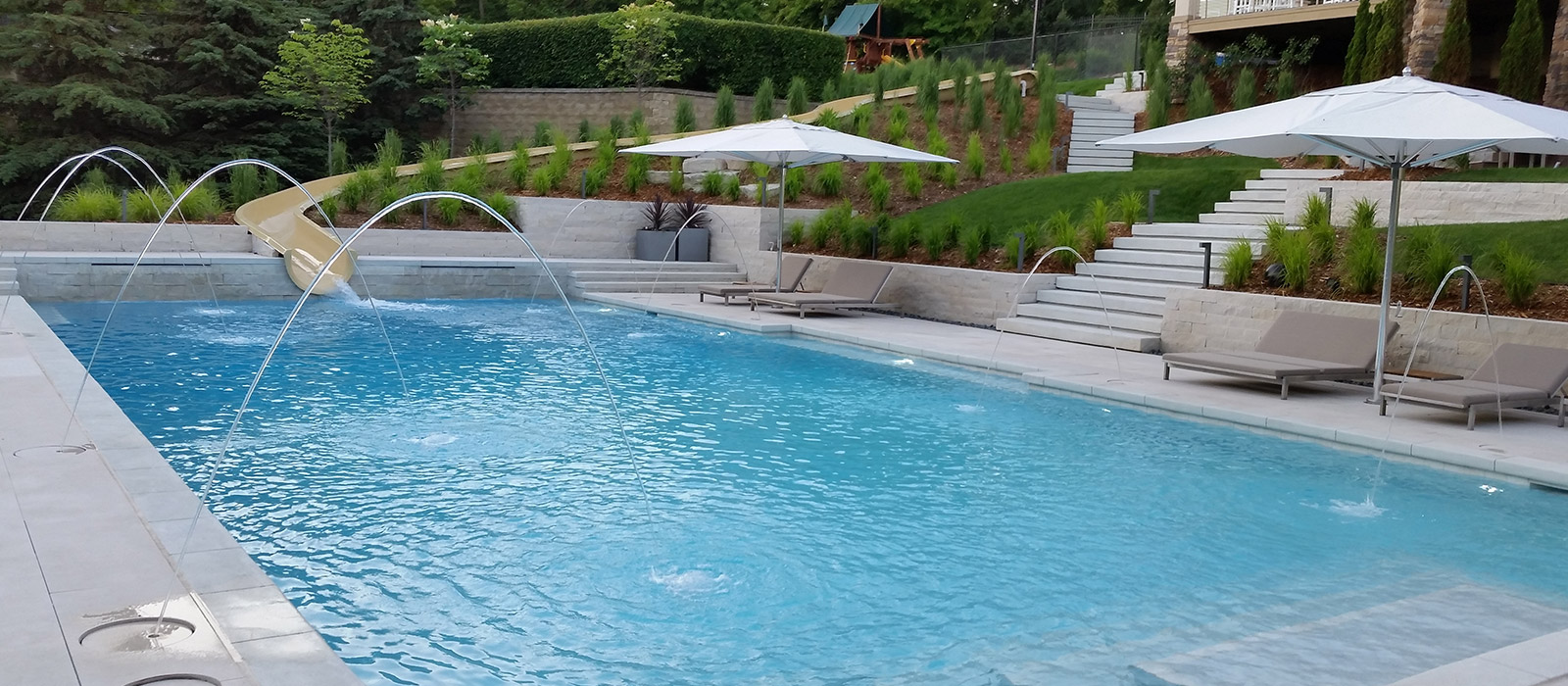 In-ground Concrete Pool With Built-in Slide Using the Natural Slope of the Landscape